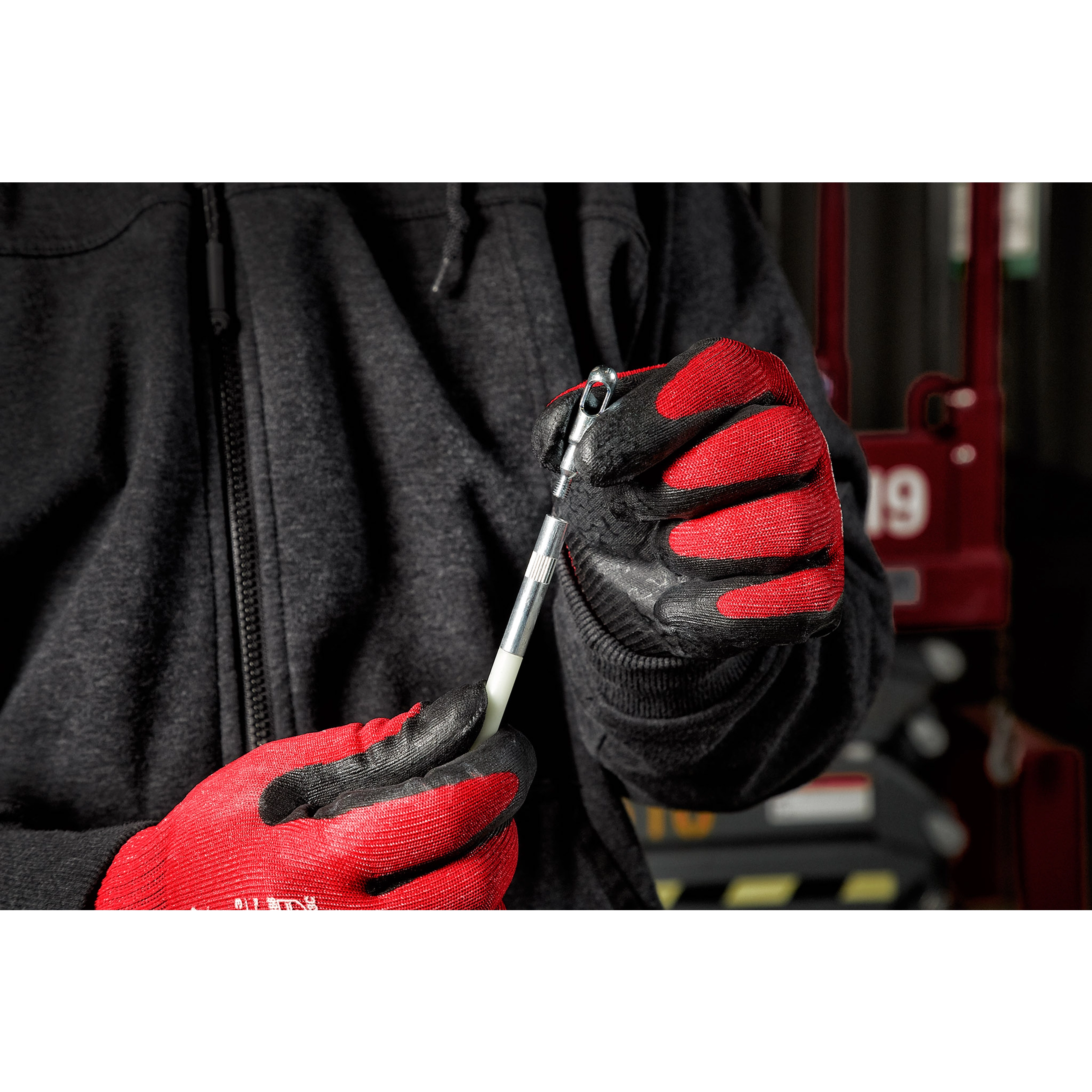 Person wearing red and black gloves holding a part from the 3pc Fish Stick Tip Accessory Kit in a workshop setting.
