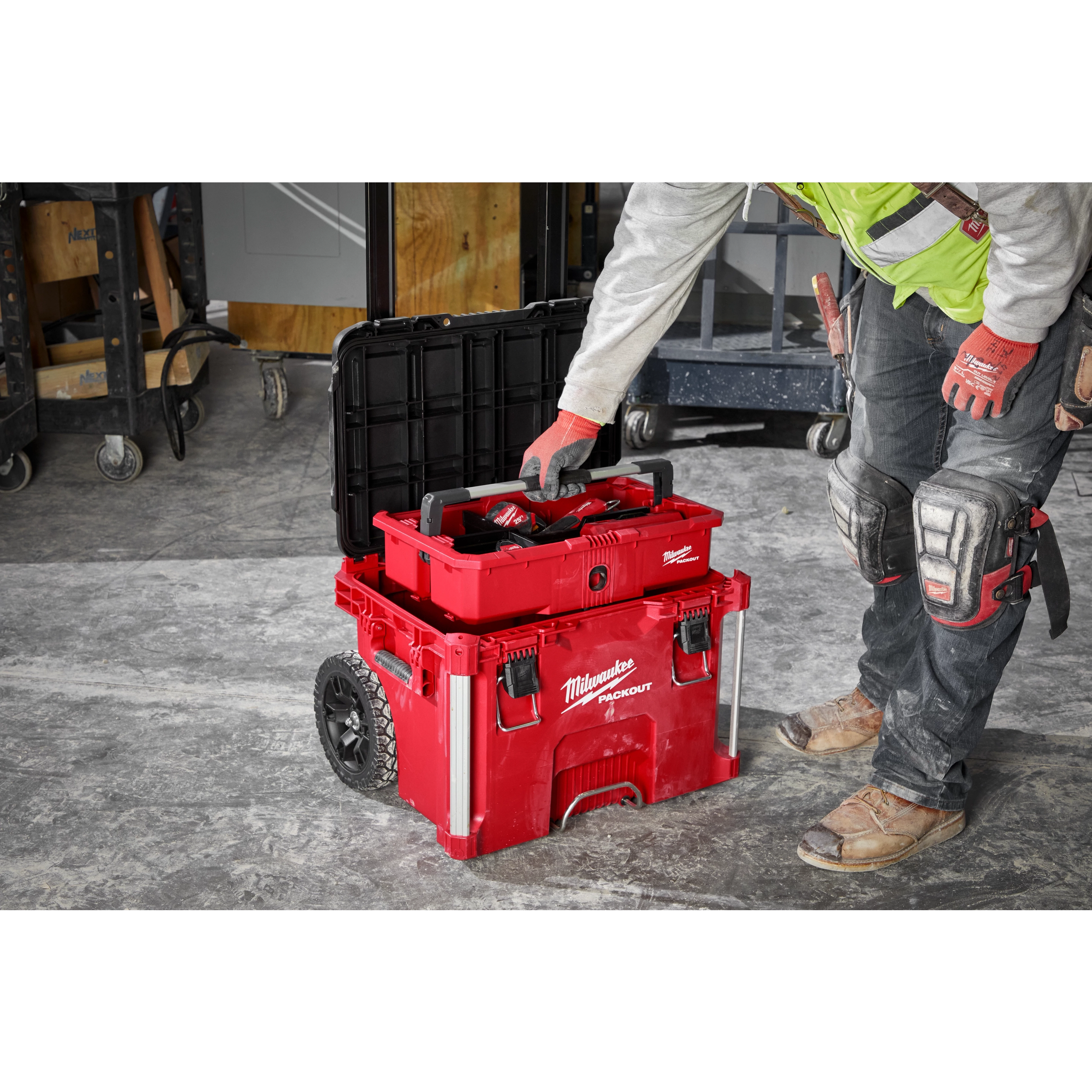 Image of a worker on a jobsite using the Milwaukee PACKOUT Rolling Tool Box with PACKOUT Tool Tray