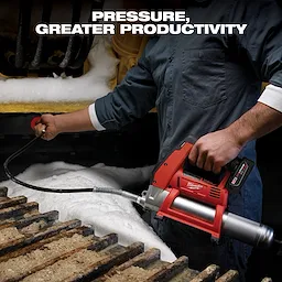 A person in blue coveralls uses a red Milwaukee grease gun on a piece of industrial machinery. Snow and ice surround the machine parts. The text "Pressure, Greater Productivity" is written at the top of the image.