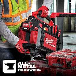 A construction worker with gloves is holding a Milwaukee PACKOUT tool bag, demonstrating its all-metal hardware feature.