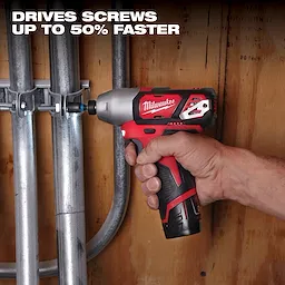 A person uses a red and black power driver tool from the M12 Cordless 4-Tool Combo Kit to fasten a screw to secure metal pipes against a wooden wall. Text above reads, "DRIVES SCREWS UP TO 50% FASTER."