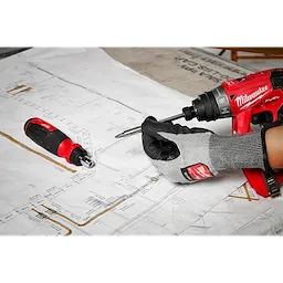 A gloved hand using a 14-in-1 Ratcheting Multi-Bit Screwdriver with a drill over architectural blueprints, with another screwdriver lying nearby.