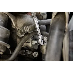 A close-up image of a 10mm Milwaukee combination wrench being used to tighten a bolt in a mechanical assembly.