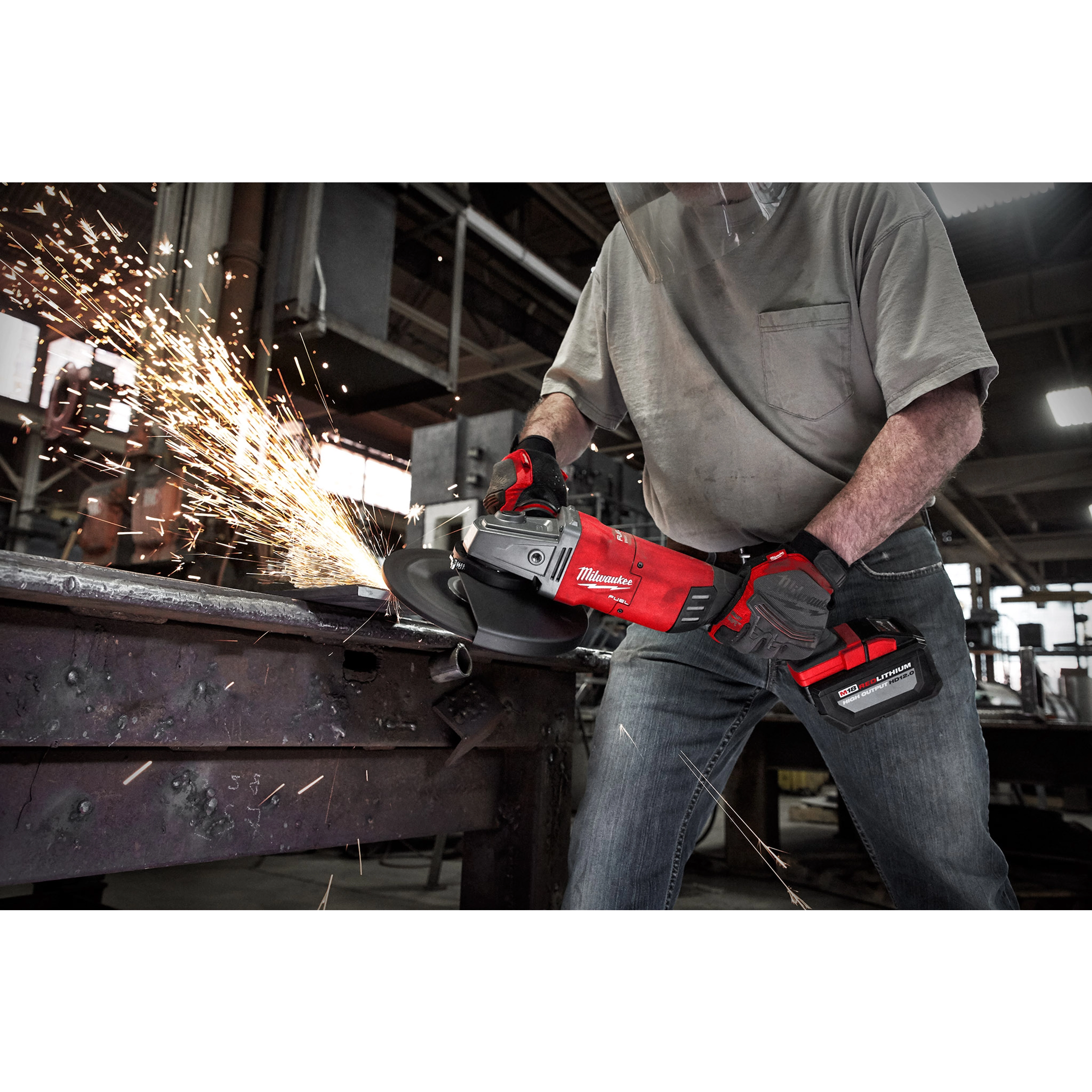 Person using the M18 FUEL 7” / 9” Large Angle Grinder (LAG) to cut metal, producing sparks in an industrial setting.