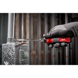 A gloved hand uses the 14-in-1 Ratcheting Multi-Bit Screwdriver to tighten a screw on a metallic industrial component.