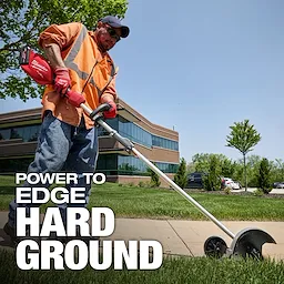Worker using an M18 FUEL QUIK-LOK Edger Attachment to edge grass along a sidewalk near an office building.