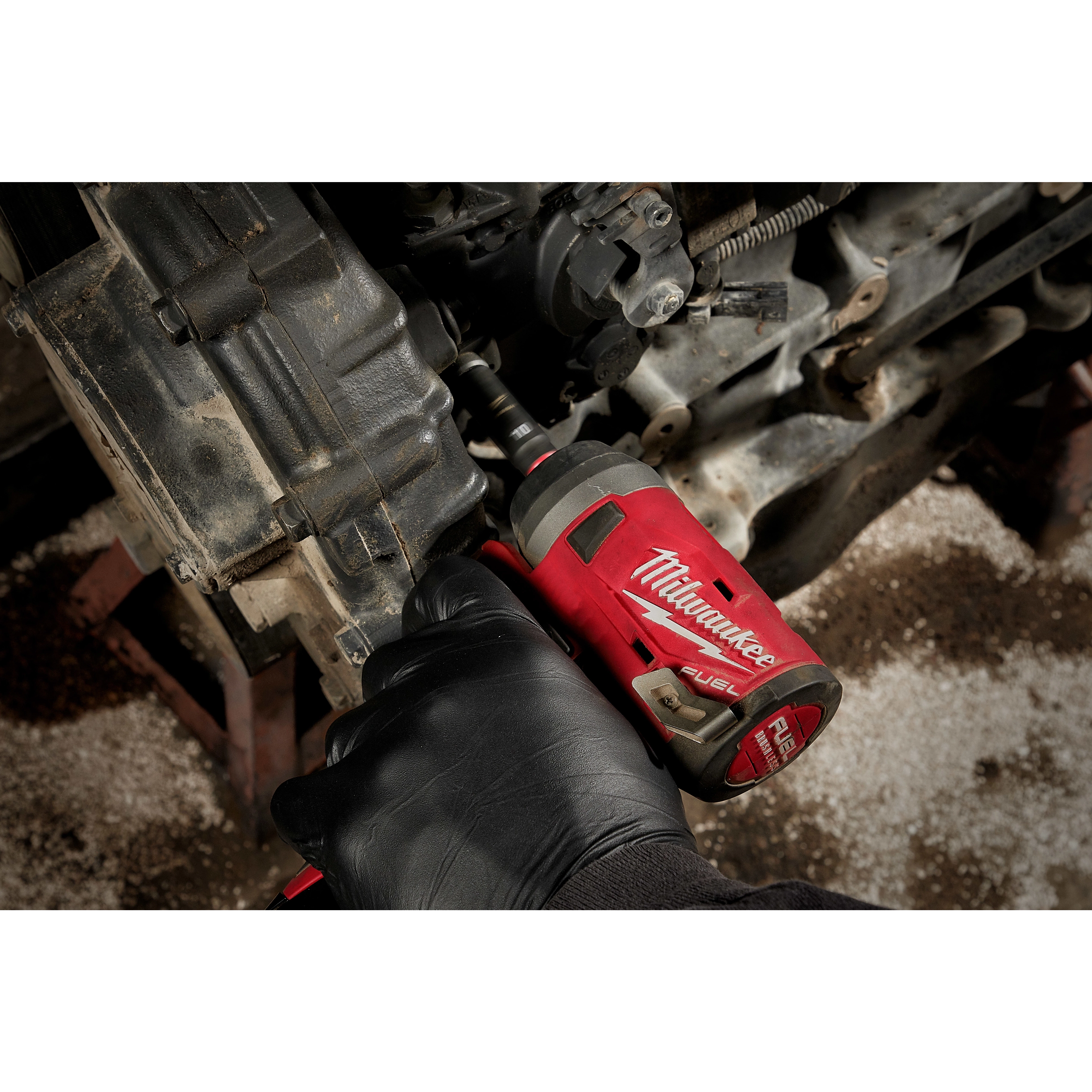 A person uses a red Milwaukee FUEL tool with a SHOCKWAVE Impact Duty 1/4" Drive 14MM Deep 6 Point Socket to work on a vehicle engine.