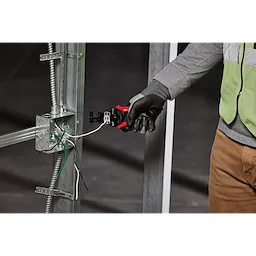 A person wearing gloves uses an Automatic Wire Stripper & Cutter to strip and cut wires attached to a metal frame.