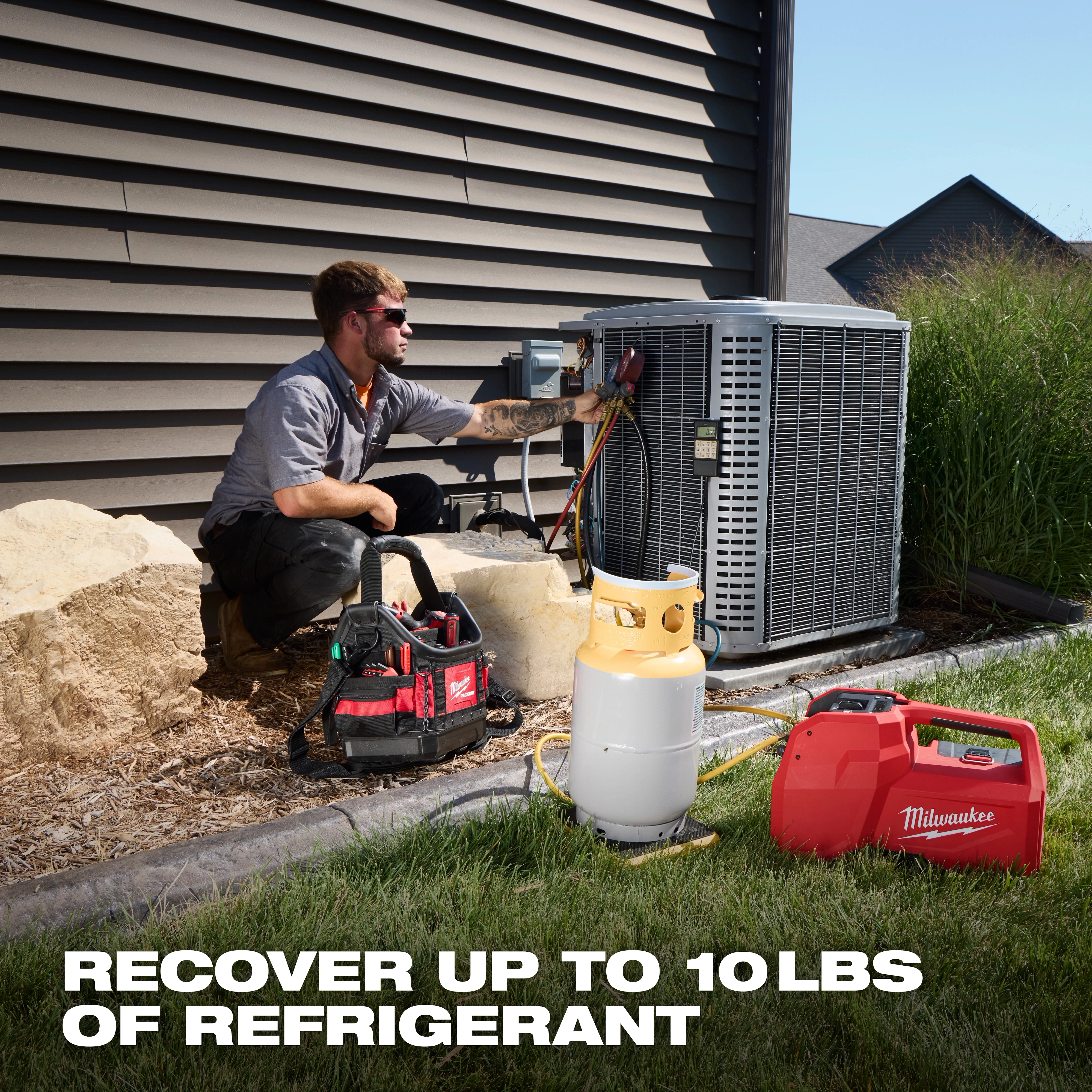 Technician using an M18 Brushless Refrigerant Recovery Machine next to an HVAC unit.