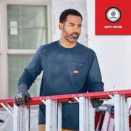 Man wearing a dark blue GRIDIRON Pocket T-Shirt - Long Sleeve Anti-odor, standing behind a red and silver ladder, holding it with both hands.
