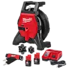 The image shows a Milwaukee drain cleaning machine set. It includes a red and black drain cleaner, a battery charger, two M12 batteries, two cable attachments, and a strap with a Milwaukee logo. The main device has a coiled cable and a handle on top.