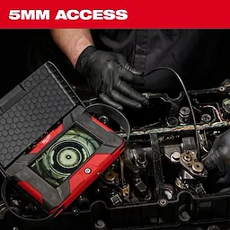 A mechanic uses the M12™ Auto Shop Borescope with Wi-Fi® File Sharing to inspect an engine. The borescope screen shows detailed internal components, aiding in diagnostics and repair. The product is designed for 5mm access, perfect for tight spaces. The mechanic wears black gloves and uses various tools.