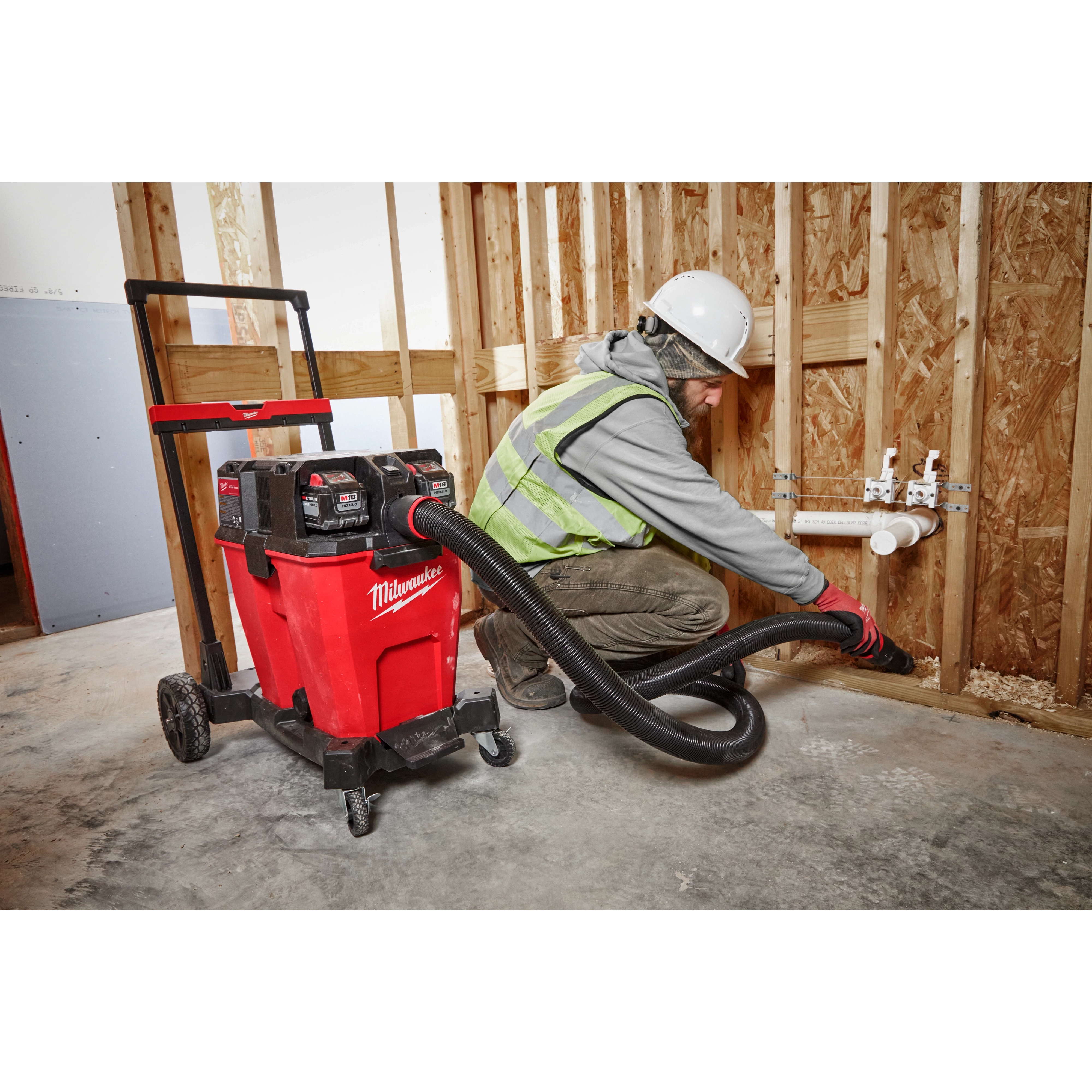 Person using the M18 12 Gallon Dual-Battery Wet/Dry Vacuum Kit to clean a construction site.