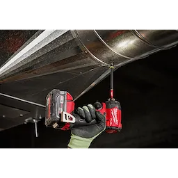 A worker's gloved hand uses the SHOCKWAVE Impact Duty 5/16" x 6" Magnetic Nut Driver with a power drill to fasten a metal sheet.