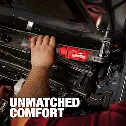 A person uses an M12 FUEL™ 1/4" Ratchet on a car engine. The tool is red and black with the Milwaukee logo visible. Text reading "UNMATCHED COMFORT" appears in the bottom left corner. The image emphasizes ease of use in tight spaces.