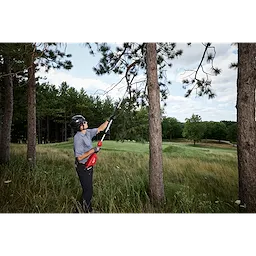 Person trimming high tree branches with M18 FUEL QUIK-LOK Hedge Trimmer Attachment and QUIK-LOK Brushless Pole Saw.