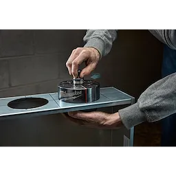 Person using a Milwaukee Draw Stud to punch a hole in a metal surface, creating a precise and clean cut.