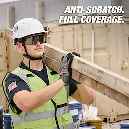 Worker wearing Wrap Around Safety Glasses - Mirrored Anti-Scratch Lenses, hard hat, gloves, and safety vest carrying a wooden beam.