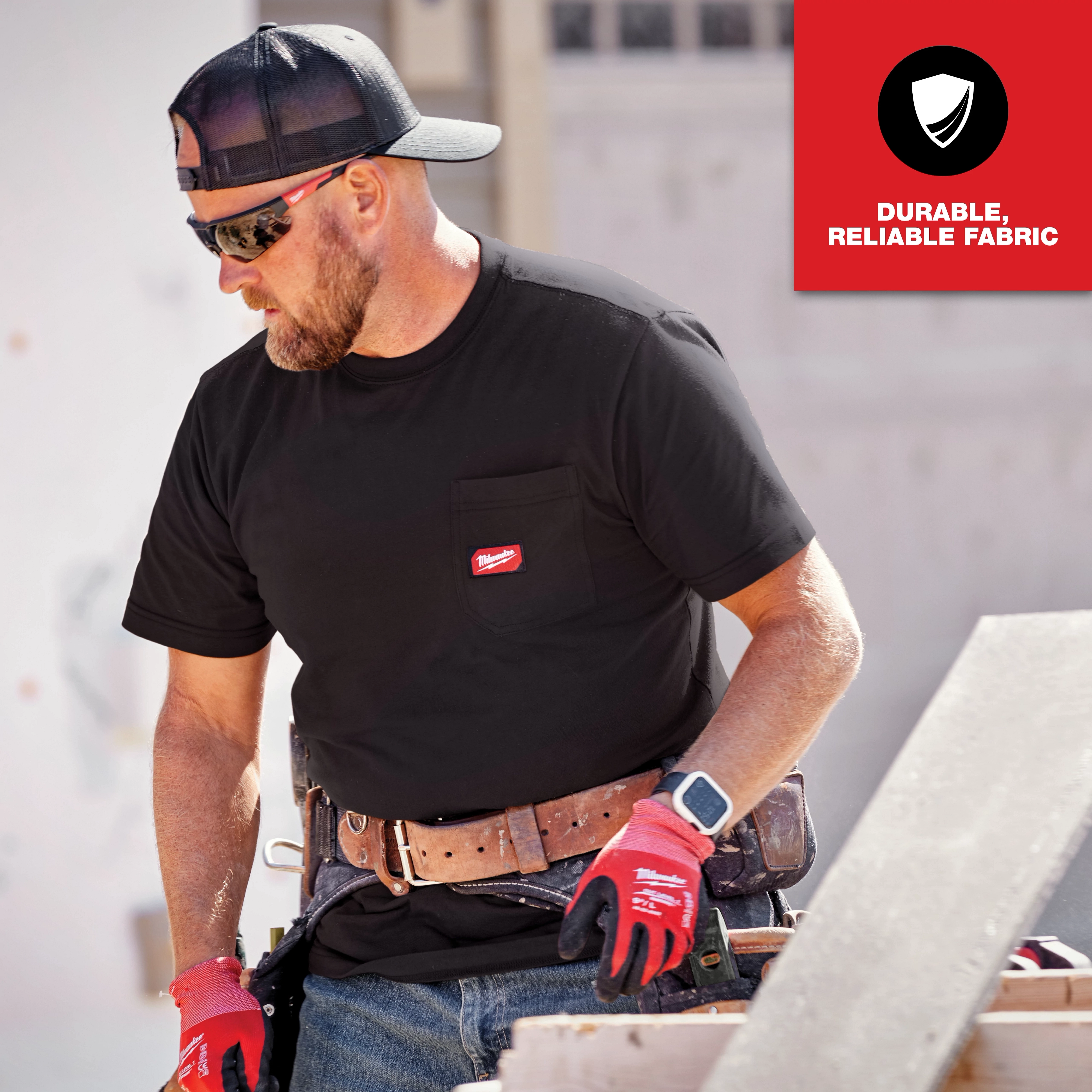 Man wearing a black GRIDIRON Pocket T-Shirt - Short Sleeve, working on a construction site, with "Durable, Reliable Fabric" text in the corner.