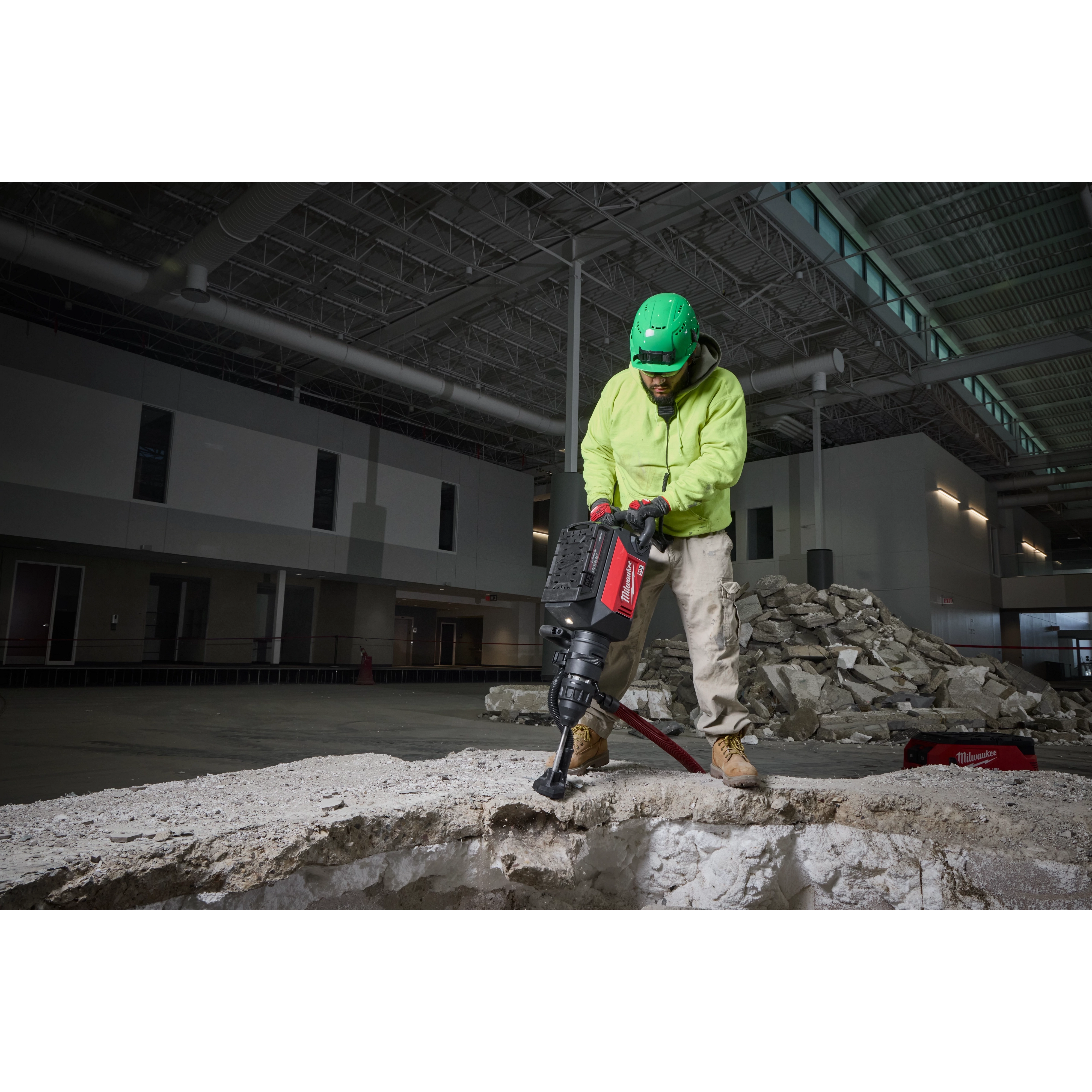 Construction worker using the MX FUEL 27 lb SDS MAX Demolition Hammer to break concrete in an industrial building.