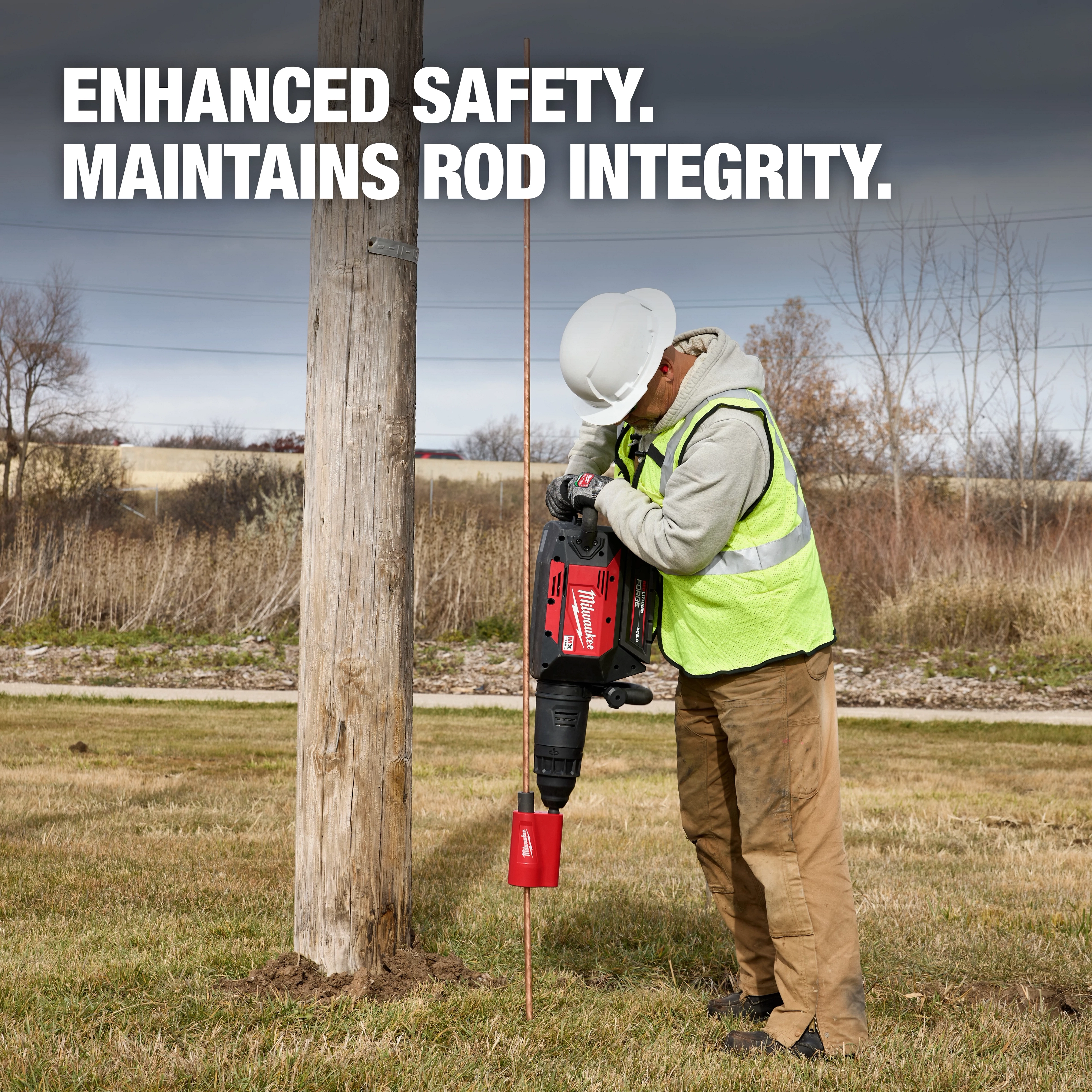Worker using SDS Max Side Load Ground Rod Driver on a copper rod by a wooden pole. Text reads: "Enhanced Safety. Maintains Rod Integrity."