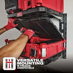 Hands placing a red PACKOUT Shelf for E-Track on a metal mounting system. Text overlay at the bottom reads "Versatile Mounting, E-Track Compatible."