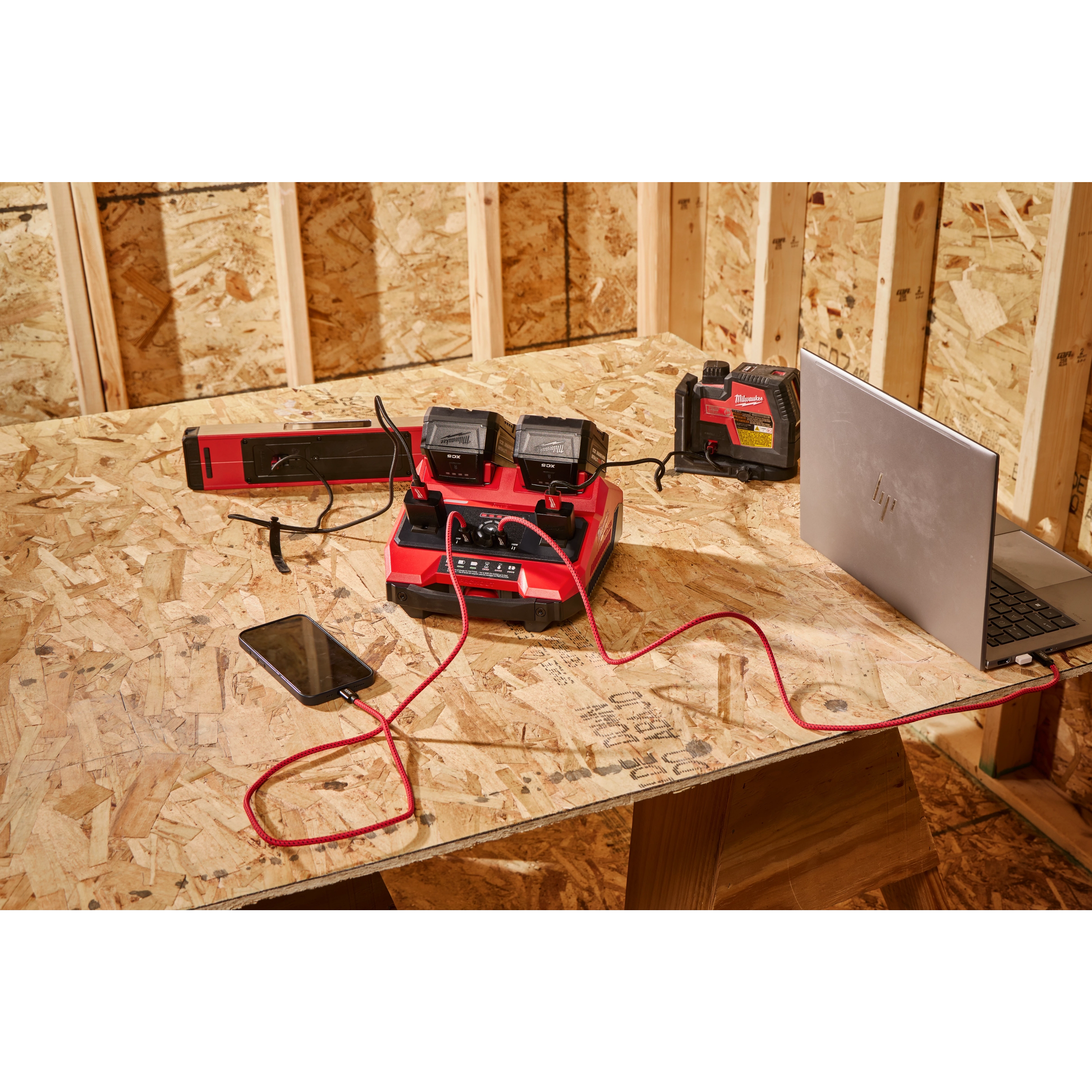 M18 TOP-OFF 350W Power Supply & Charger with devices connected on a plywood worktable in a framed room.