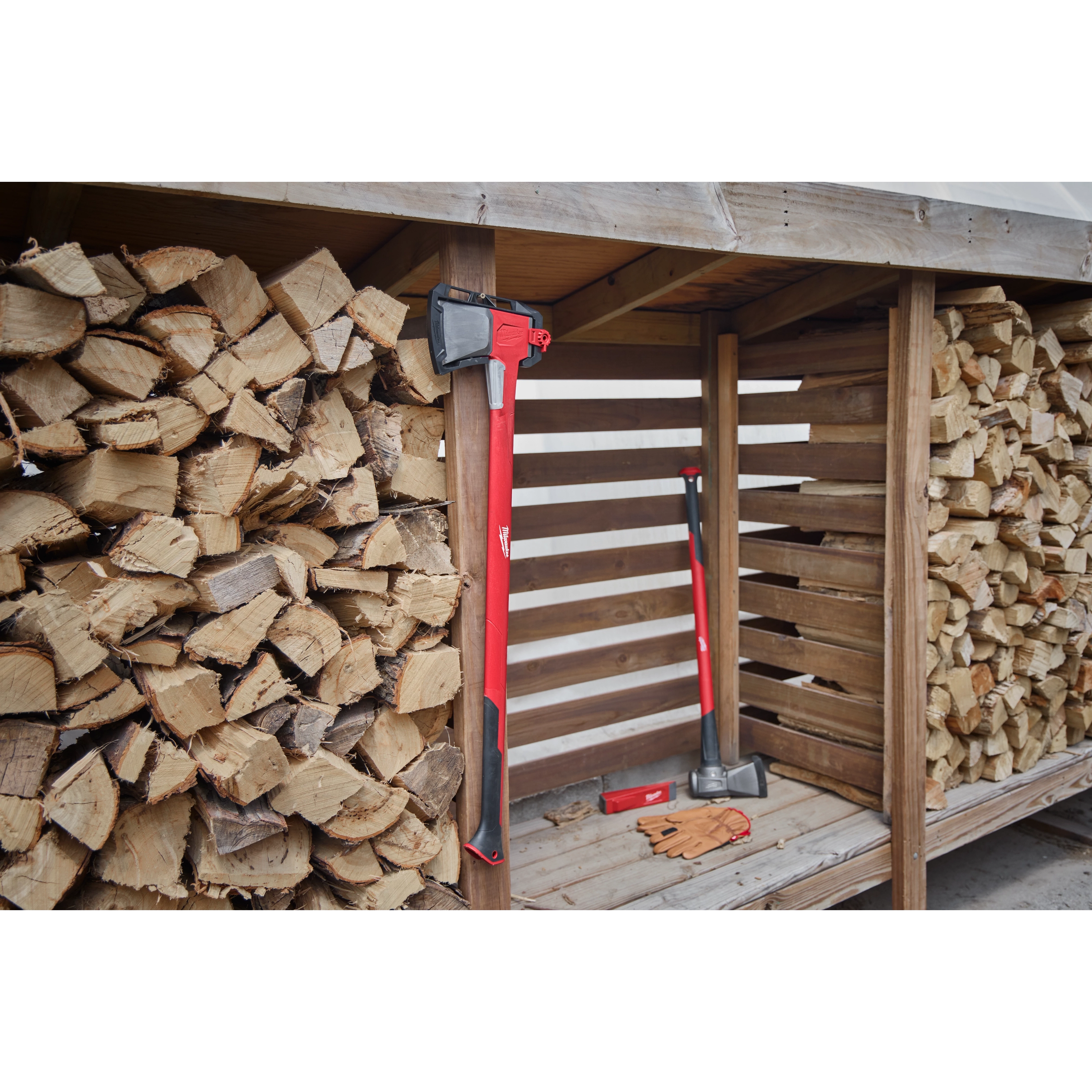 The product image features the Wood Splitting Family, which includes a red and black axe and a splitting maul arranged next to a large stack of split logs in a wooden storage shed. Gloves and another tool accessory rest on the wooden floor.