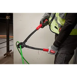 A worker uses 17" Utility Cable Cutter with red handles to cut a thick green cable, wearing gloves and a high-visibility vest.