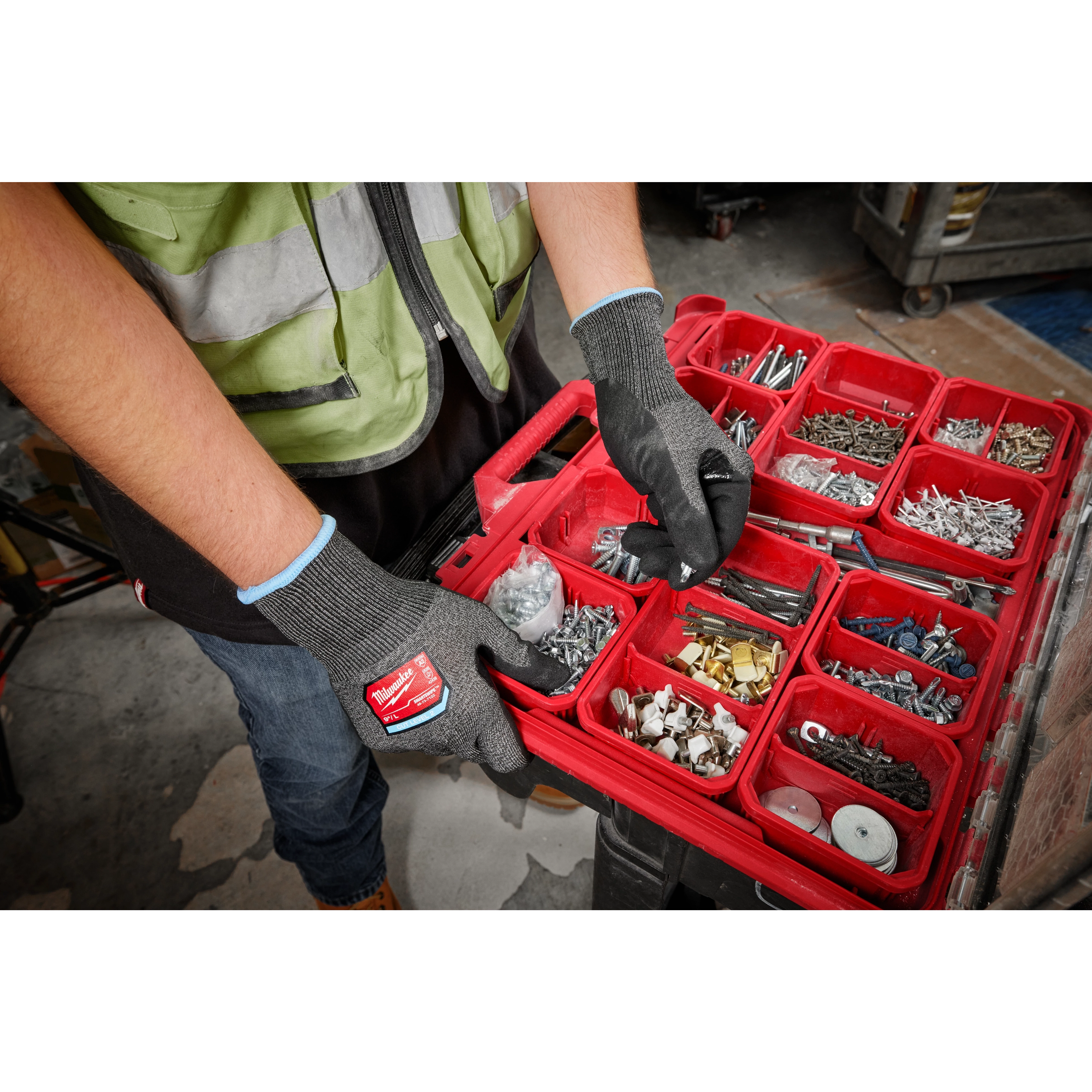 Person wearing Cut Level 2 High-Dexterity Nitrile Dipped Gloves - L, sorting small hardware items in a red compartmented box.