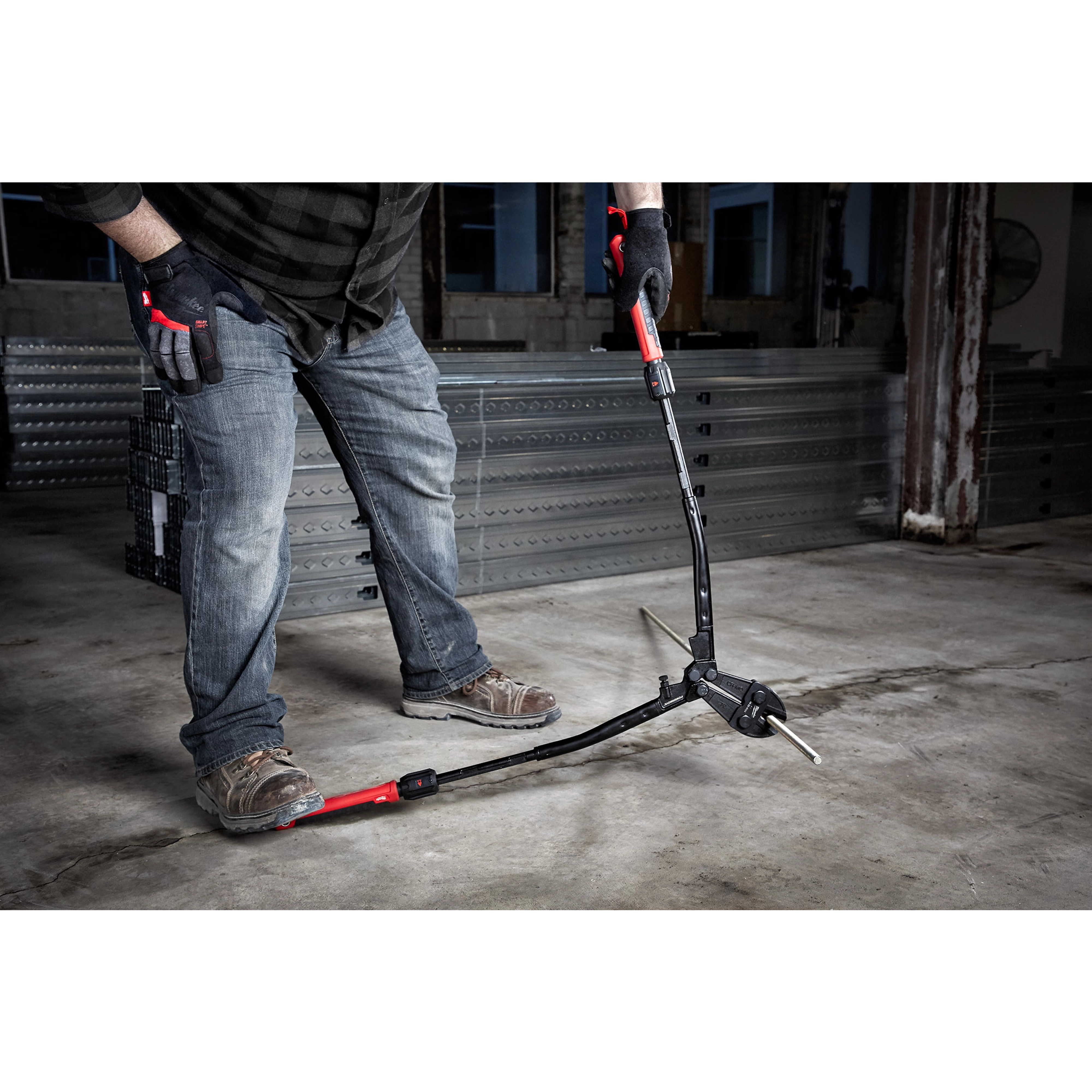 A person uses the 24" Adaptable Bolt Cutter with Extendable Arms, applying pressure to cut a metal bar in an industrial setting.