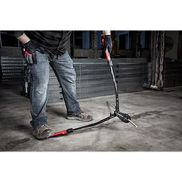 A person uses the 24" Adaptable Bolt Cutter with Extendable Arms, applying pressure to cut a metal bar in an industrial setting.