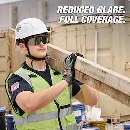 Worker wearing Wrap Around Safety Glasses with Mirrored Anti-Scratch Lenses, safety helmet, and gloves, carrying a wooden beam.