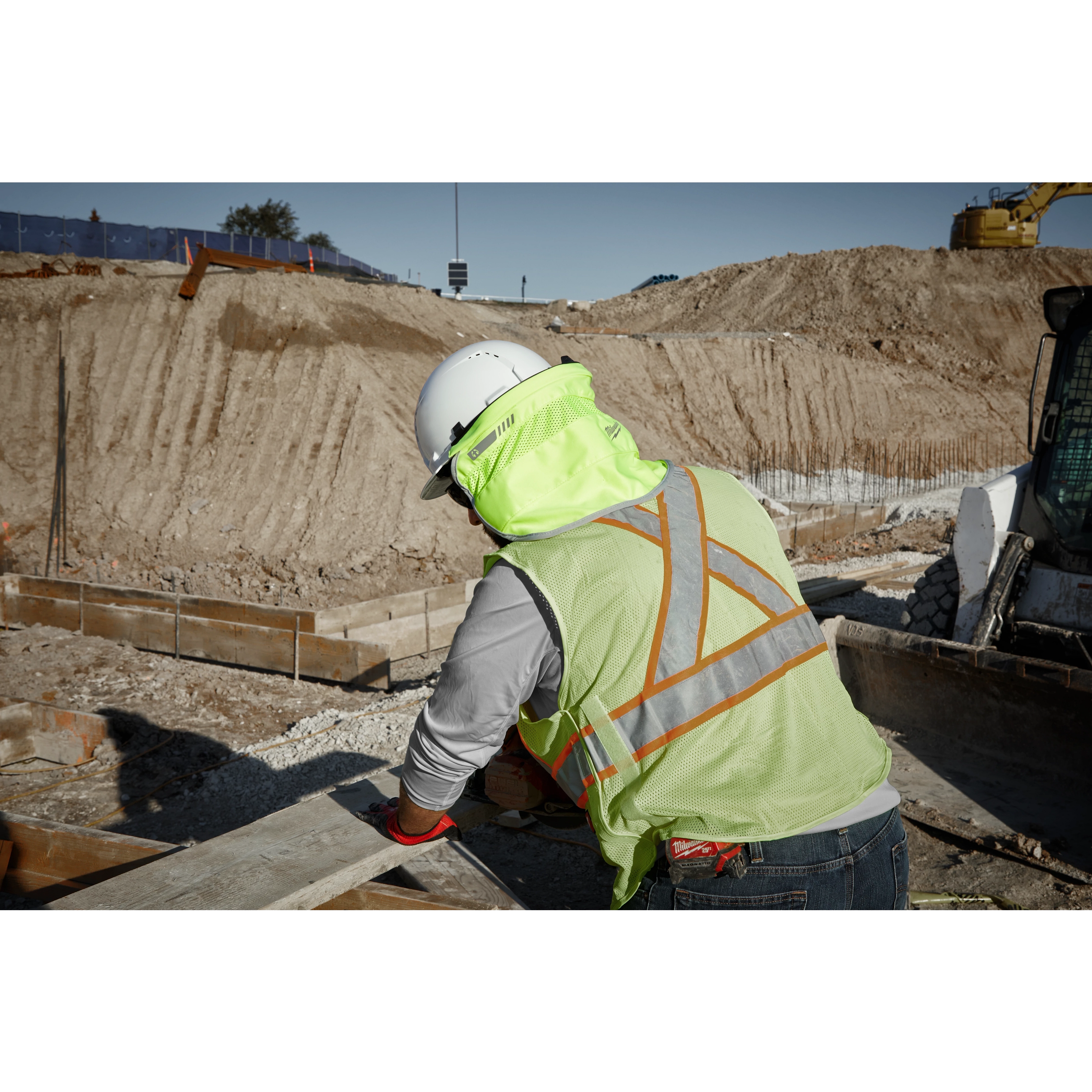 Worker wearing the BOLT Sunshade attached to a hard hat while working outside on the jobsite