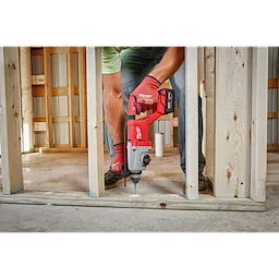 Man using the M18 Brushless 1” SDS Plus D-Handle Rotary Hammer to drill into the base of a wooden structure under construction.