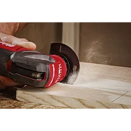 A person uses the MILWAUKEE OPEN-LOK 3-1/2" HCS Wood Segmented Multi-Tool Blade on a piece of wood, creating sawdust.