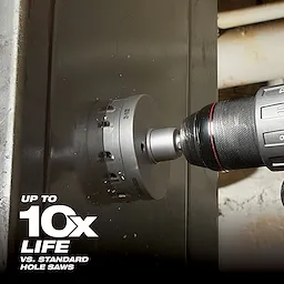 The Large Hole Cutter is attached to a power drill and is cutting through a steel surface. The image highlights that this tool offers up to ten times longer life compared to standard hole saws. The tool is cylindrical with sharp teeth around the edge for effective cutting.