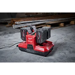 M18 & M12 Four Bay Simultaneous Super Charger with PACKOUT Compatibility; red charger with four battery slots on a workshop floor.
