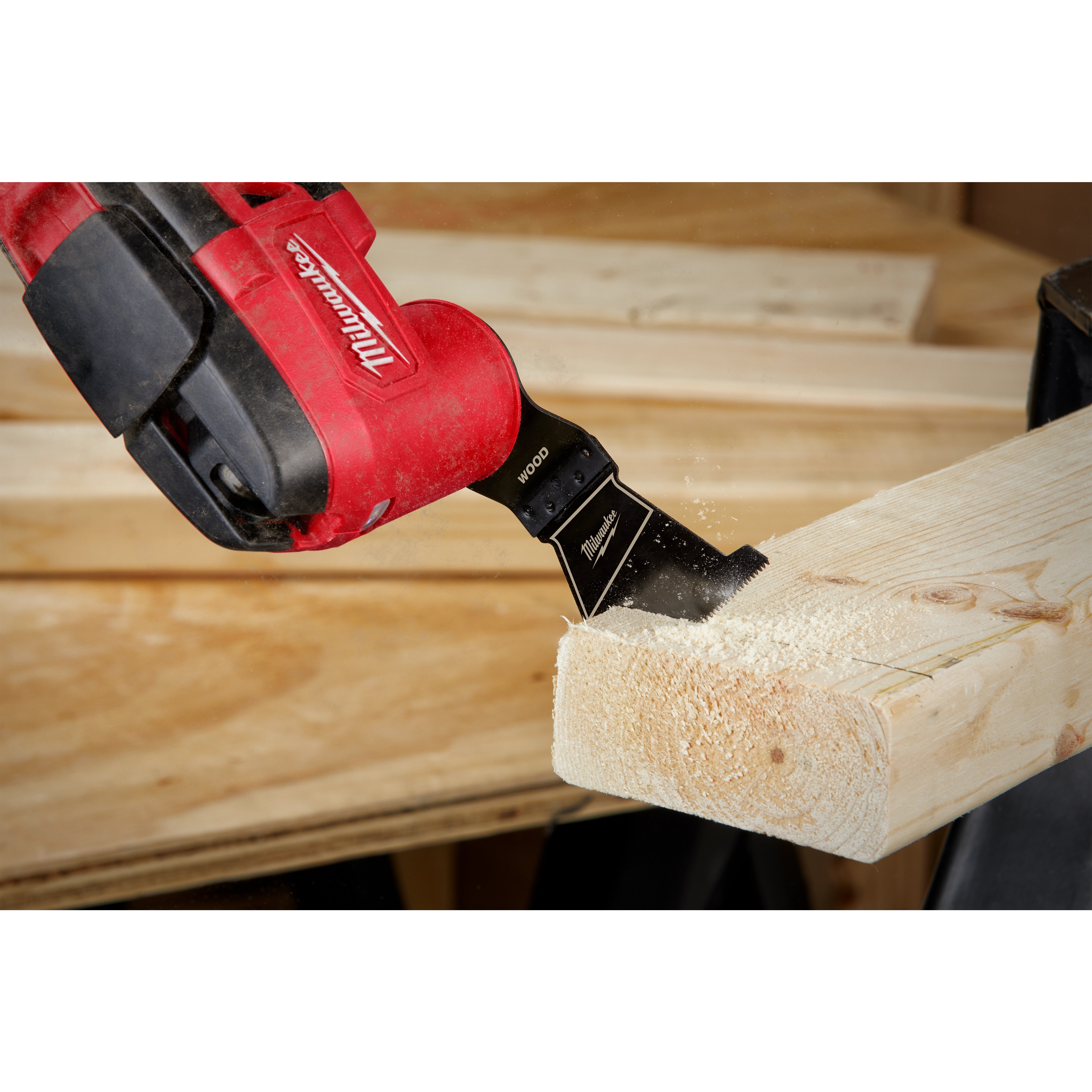 MILWAUKEE OPEN-LOK 2-1/2" HCS Wood Multi-Tool Blade attached to a red tool, actively cutting through a wooden beam.