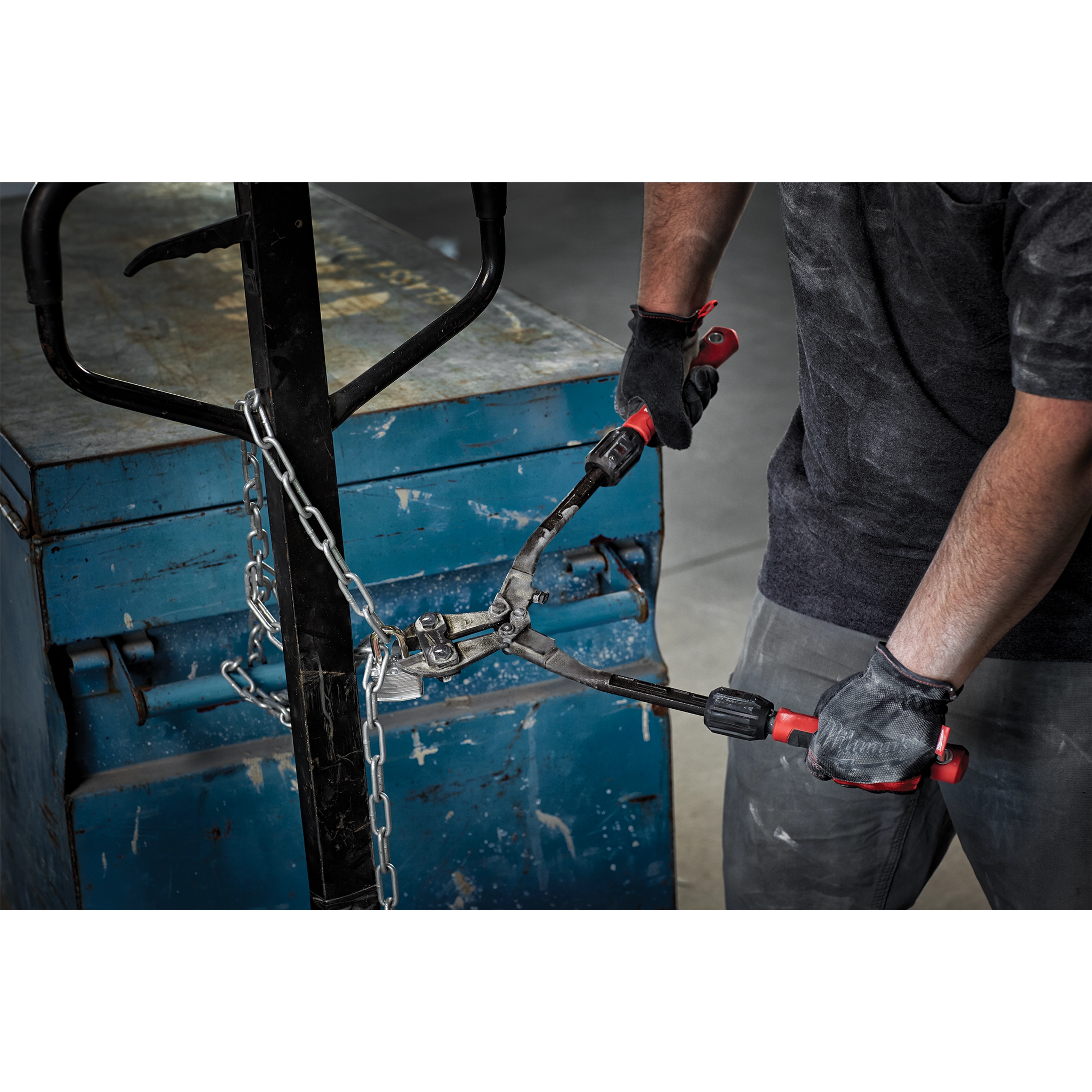 Person using 14" Adaptable Bolt Cutters with POWERMOVE Handles to cut a metal chain secured around a blue metal storage box.