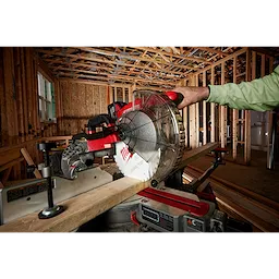 Person using the 10" 24T Ripping Circular Saw Blade on a miter saw to cut a wooden plank in a construction setting.