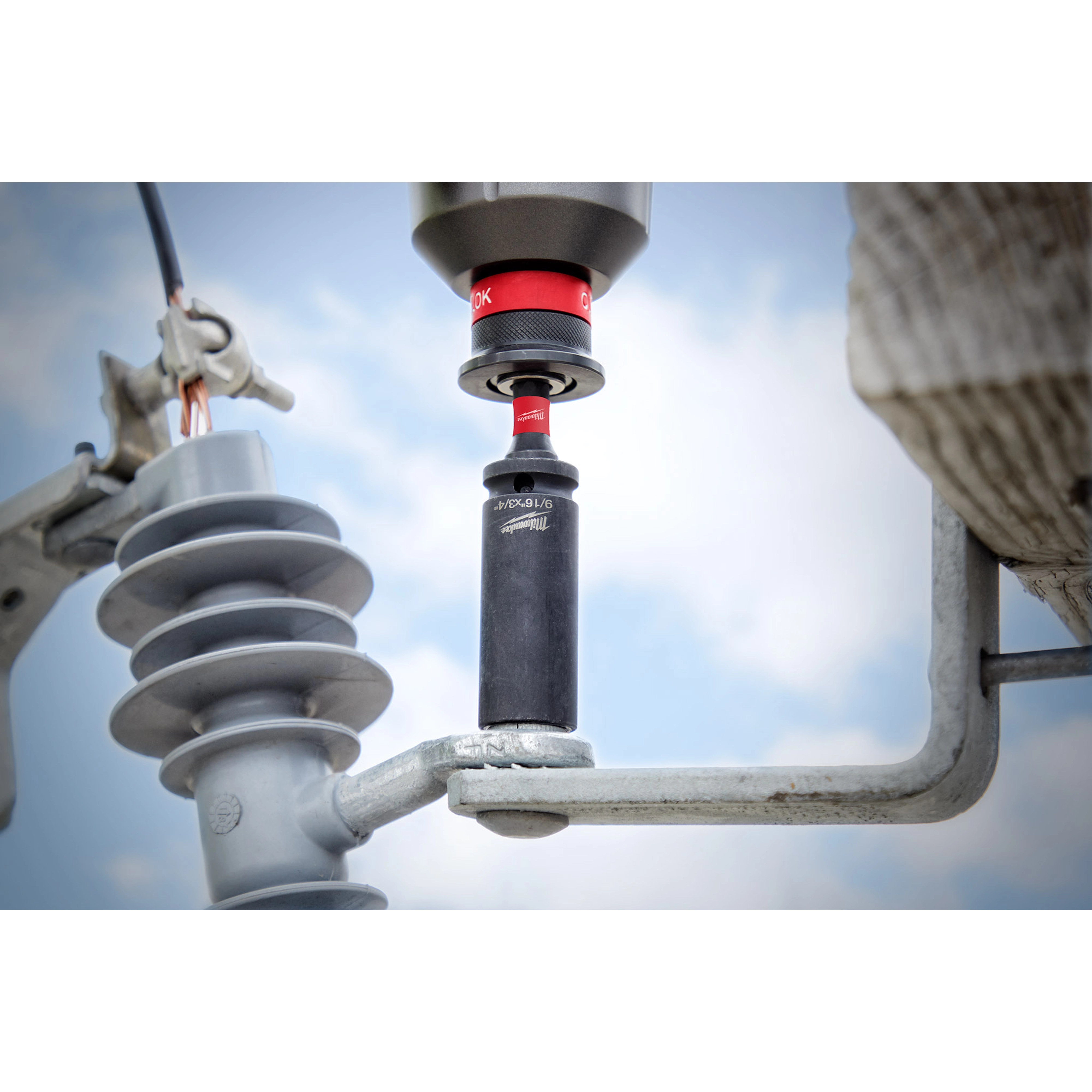 9/16"-3/4" 12PT 2-in-1 Socket attached to a power tool being used on an electrical insulator, against a sky background.
