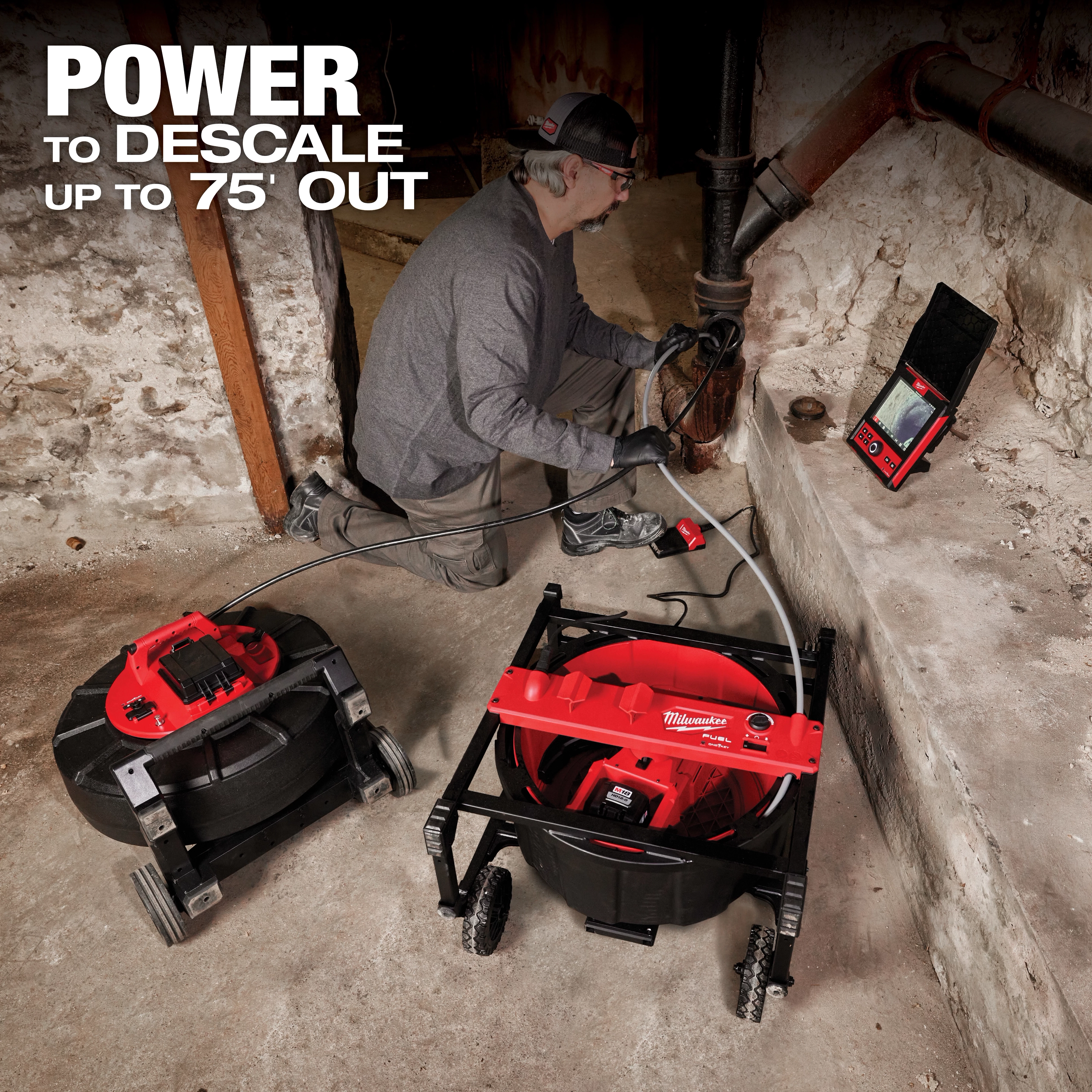 A person uses a Milwaukee descaling tool to descale pipes in a dimly lit basement. The product's slogan emphasizes its power to descale up to 75 feet out. The setup includes Milwaukee equipment such as a hose reel and display screen on the floor.