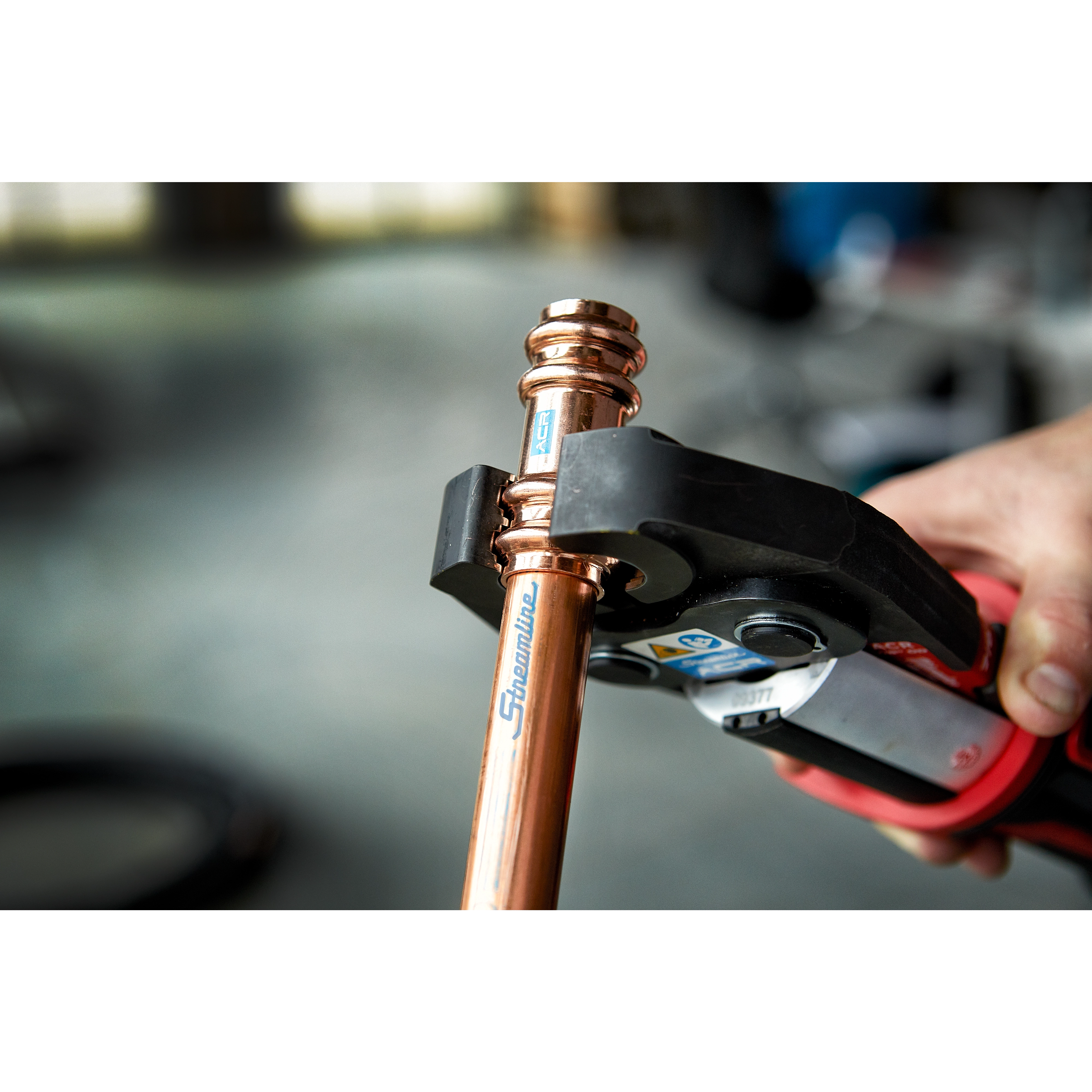 Hand holding copper pipe fitted with the M18 Force Logic Press Tool Kit with One-Key and 1/4"-7/8" Streamline ACR Jaws.