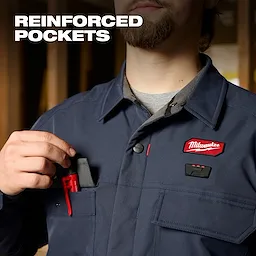 Person wearing an M12 Shirt Jacket - Navy L using a reinforced chest pocket to hold a small red tool.