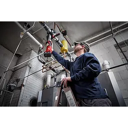 A man uses a 2½” - 4” IPS XL Ring Kit for M18 FORCE LOGIC Long Throw Press Tool to work on industrial piping in a mechanical room.