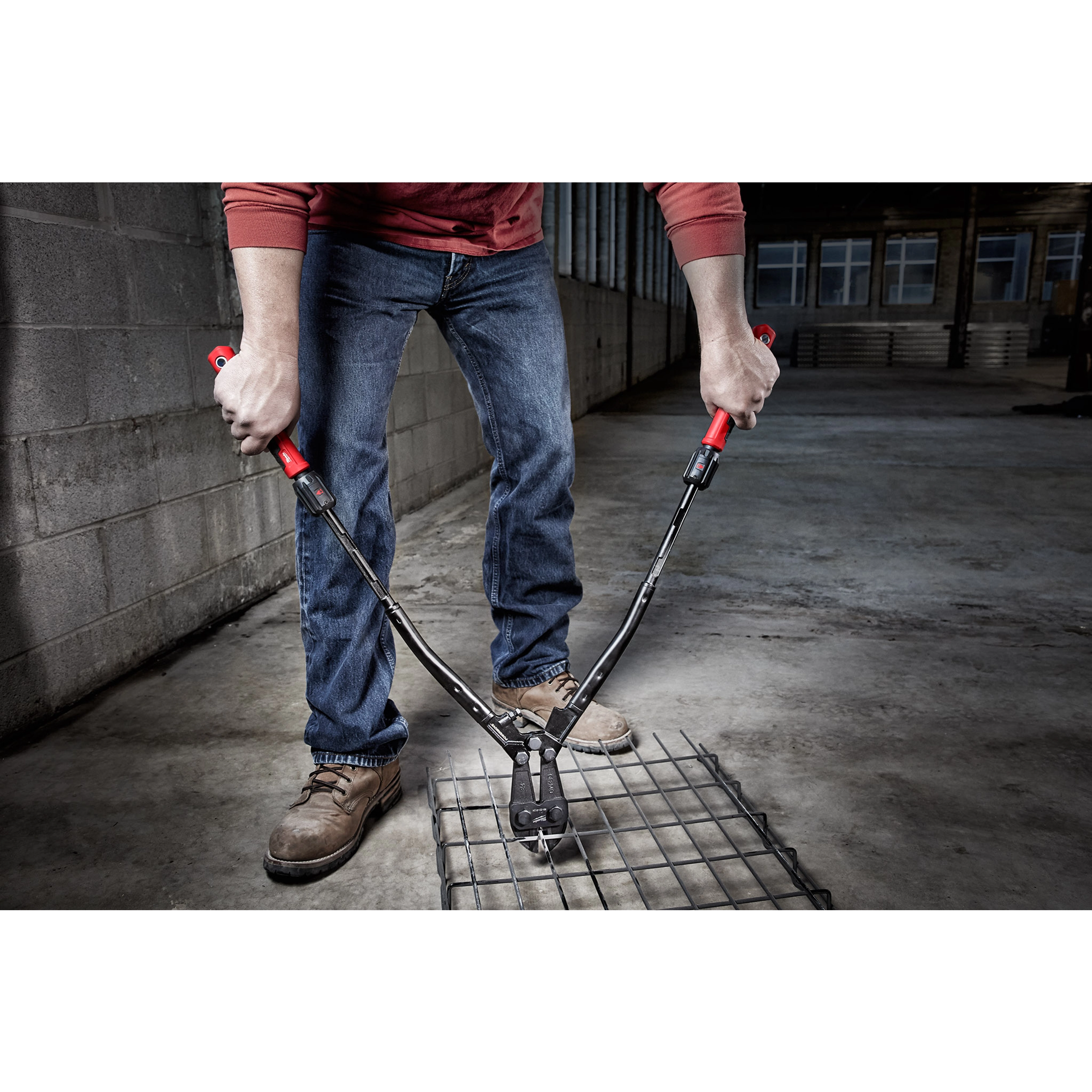 Person using 24" Adaptable Bolt Cutter with POWERMOVE Extendable Arms to cut through metal wire in an industrial setting.