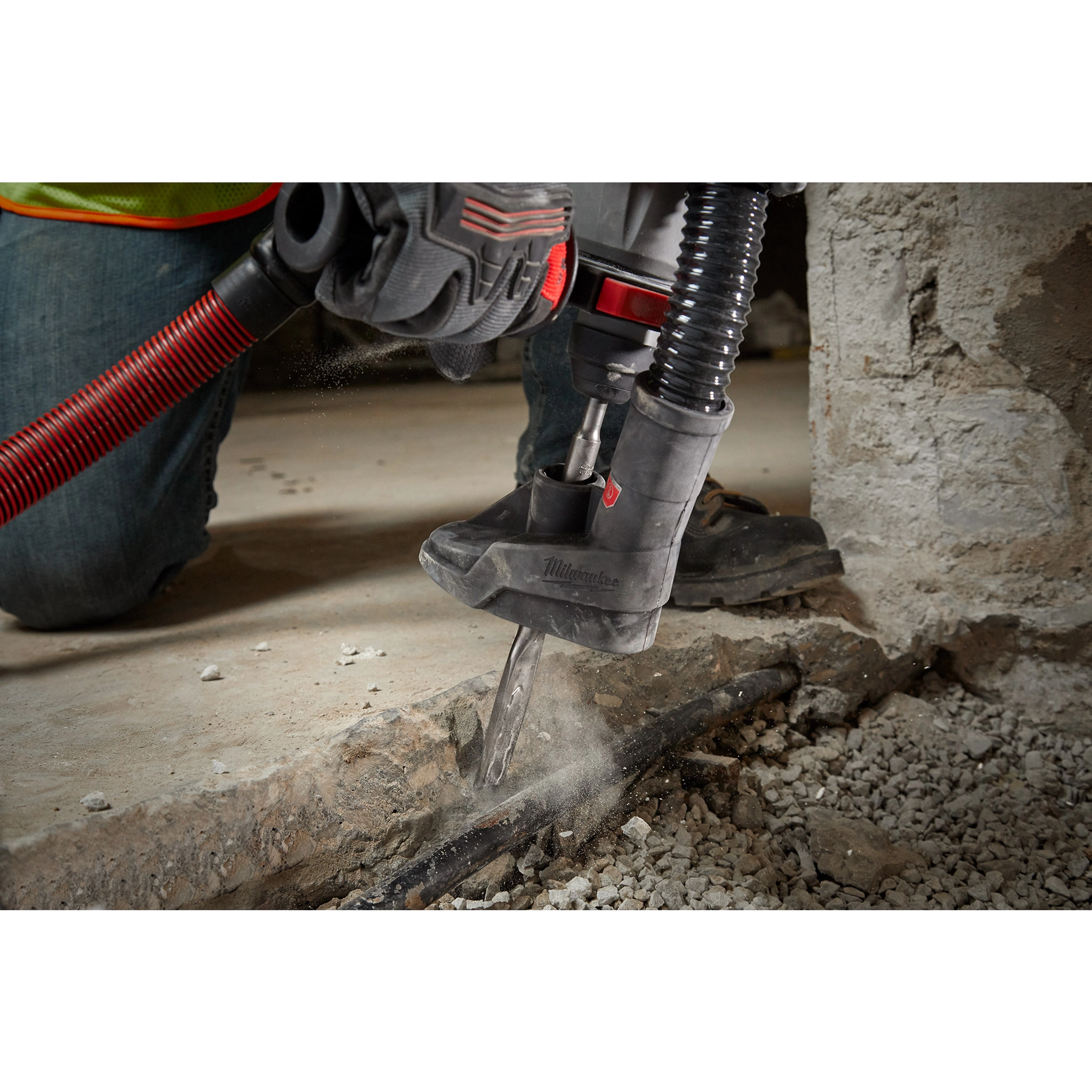 A person using the SDS+ SLEDGE 3/4"X10" FLAT CHISEL attached to a power tool to break up a concrete surface.