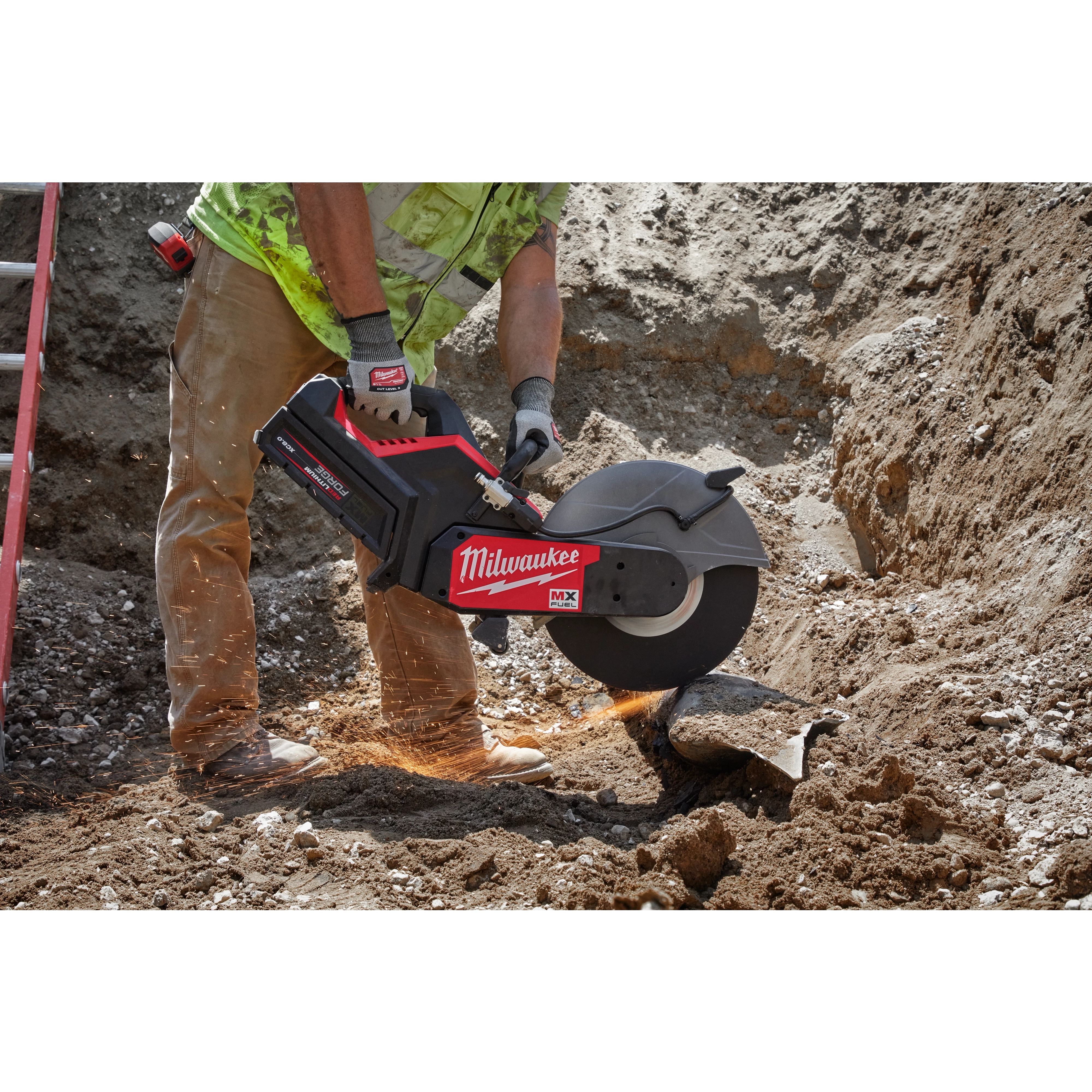 A construction worker uses a Milwaukee MX FUEL 14-inch Cut-Off Saw with RAPIDSTOP App Shot to cut a pipe in a dirt trench.