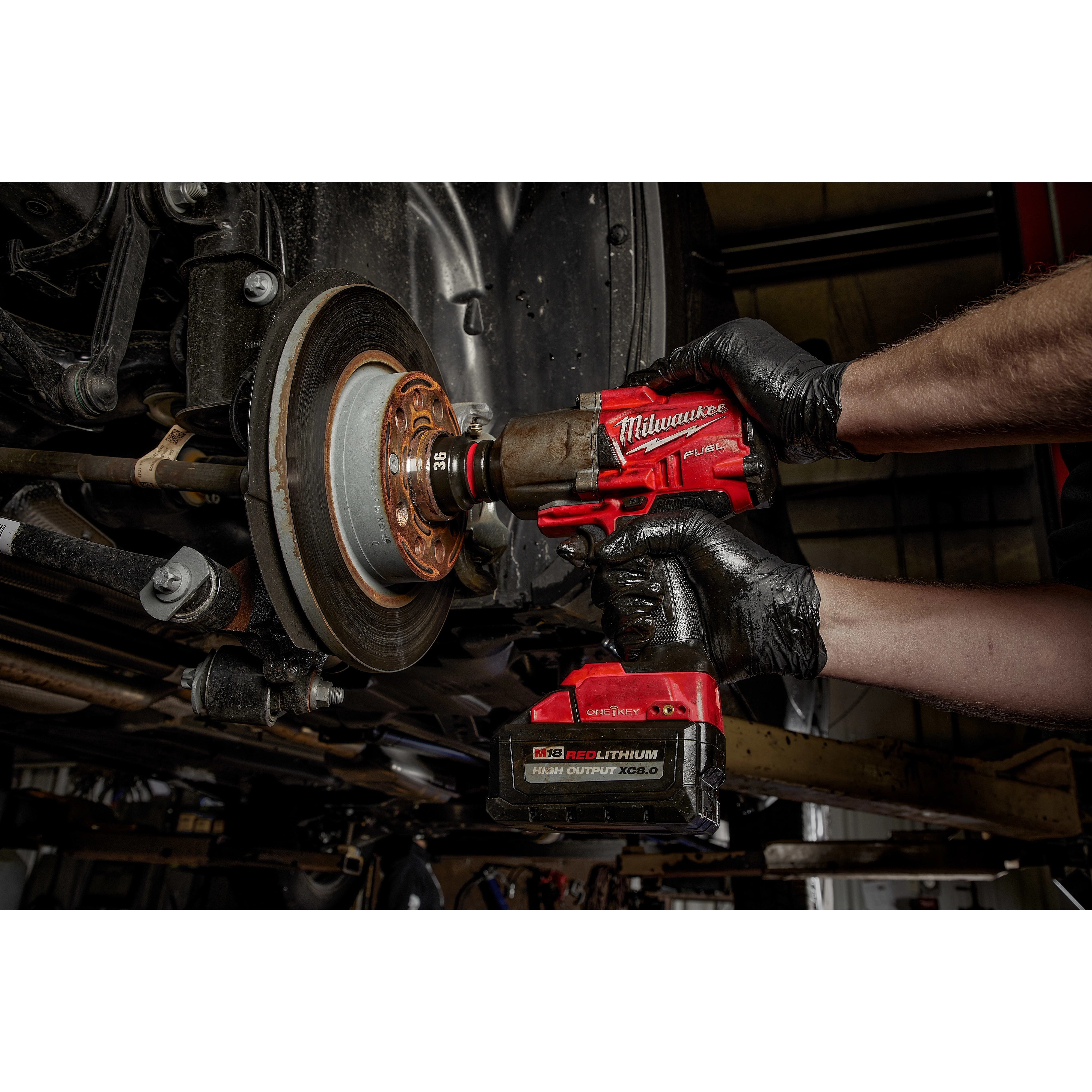 Mechanic using SHOCKWAVE Impact Duty 3/4" Drive 36MM Deep 6 Point Socket attached to a red power drill on a vehicle's brake rotor.